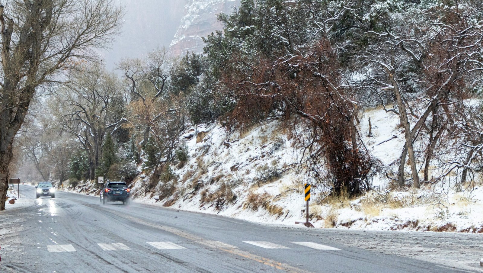 Cars driving on a snowy U.S. road during a winter storm and extreme cold weather alert